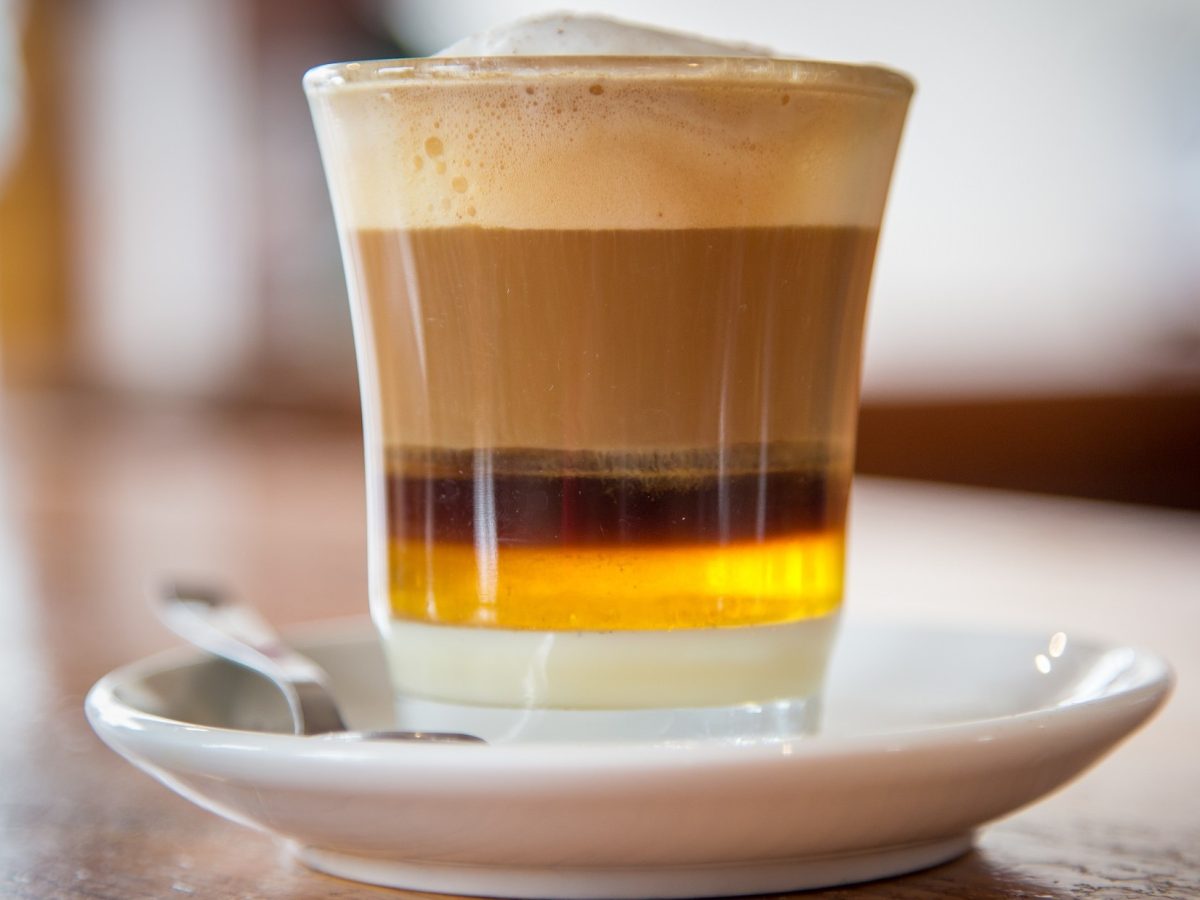 Frontal: Ein Glas mit einem Getränk, dass aus vielen Schichten besteht. Es handelt sich um eine spanische Kaffeespezialität von Teneriffa. Das Getränk heißt Barraquito.