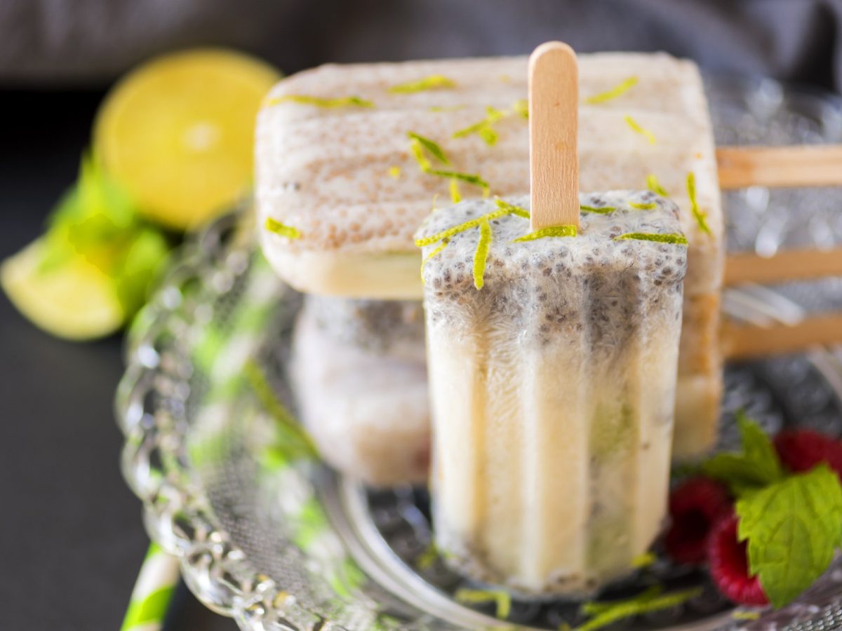 Selbstgemachte Eiscreme am Stiel mit Zitronenzesten und Minzblättern, serviert auf silbernem Teller.