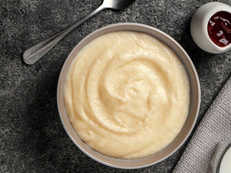 Eien weiße schale mitd em Grießpudding und einem kleinen Schälchen mit der Kirschgrütze auf grauem Untergrund. Alles direkt von oben fotografiert.