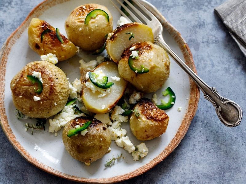 Geschmorter Kohlrabi mit Feta und Kräutern auf einem weißen Teller.