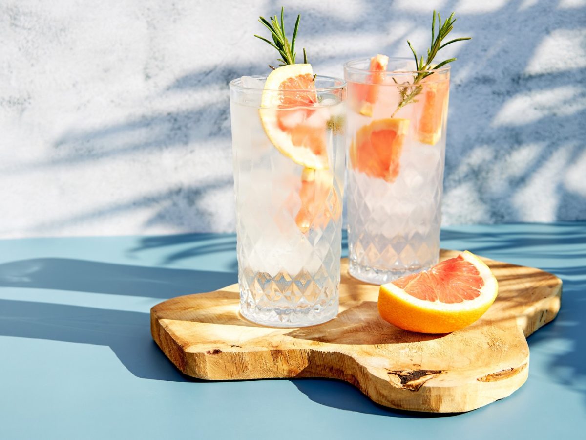 Lacascara Spritz in zwei Highballgläsern mit Grapefruit und Rosmarinzweigen.