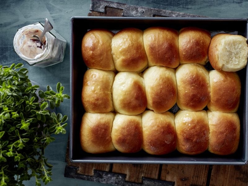 Hawaiian Buns in einer schwarzen Form auf dunkelblauem Hintergrund. Links eine Pflanze.