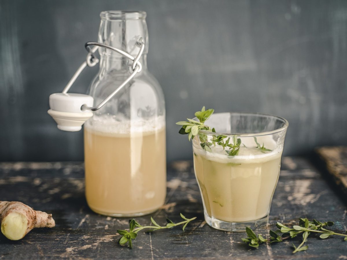 Switchel in einem Glas und einer Flasche vor grauem Hintergrund.