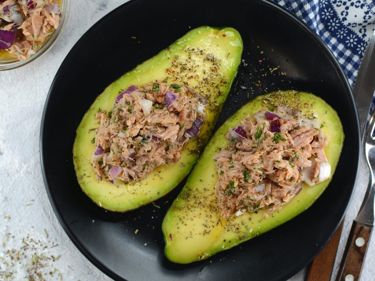 Ein schwarzer Teller mit den Avocados auf einem grauen Tisch. Alles direkt von oben fotografiert.