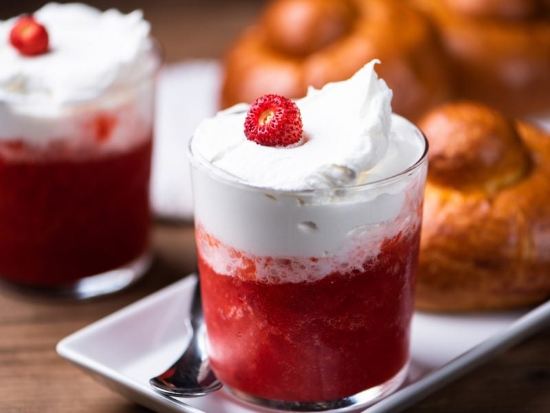 Zwei Gläser Erdbeer-Granita mit Schlagsahne und einem brioche col tuppo daneben.