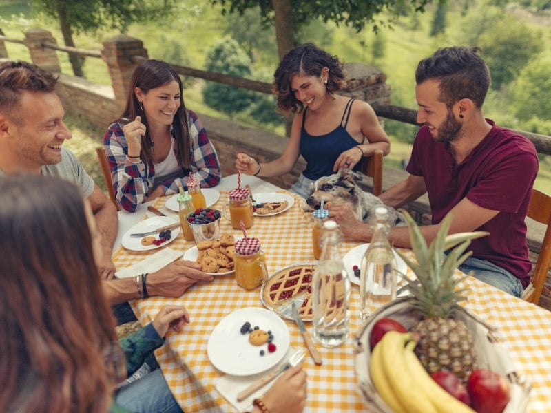 Gruppe von Freunden an einem Tisch, die ein italienisches Frühstück zu sich nimmt.