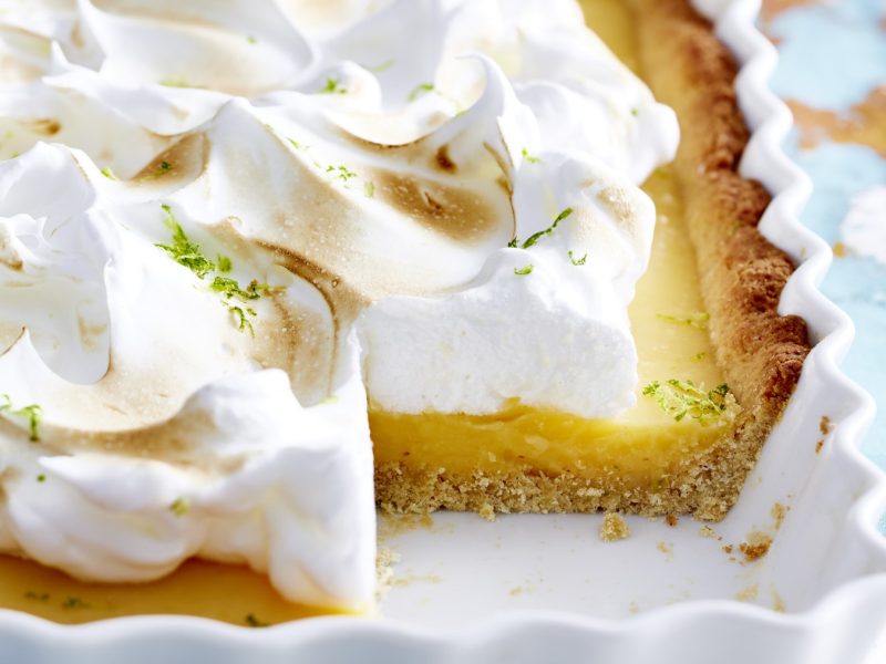 Angeschnittene Key Lime Tarte in weißer Form mit hellem Hintergrund.