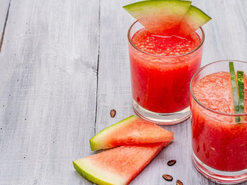 Zwei Shot-Gläser mit Wassermelonen-Mexikaner auf einem grauen Tisch von schräg oben fotografiert.