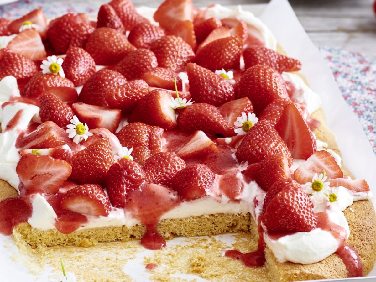 Schneller Erdbeerkuchen: Angeschnitten auf einem Backpapier mit hellem Untergrund.