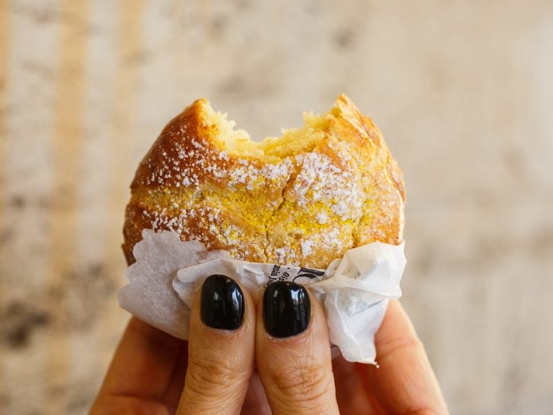 Sfogliatella frolla, die von zwei Händen hochgehalten wird.