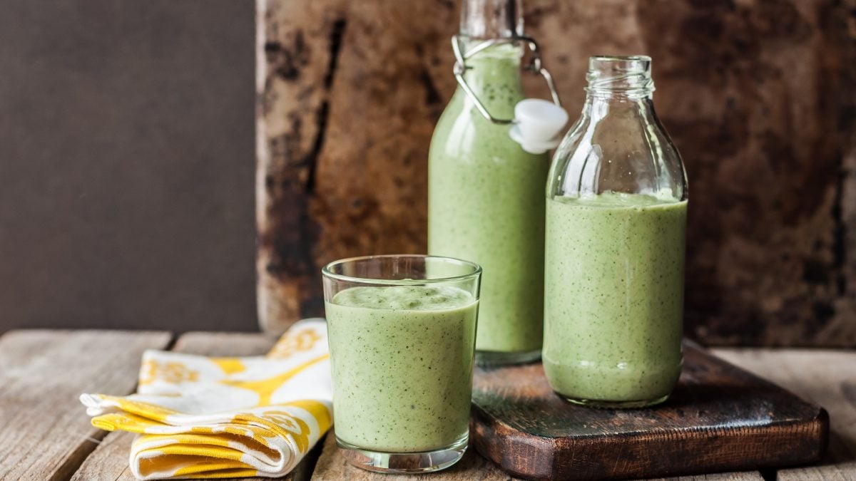 Frontal: Zwei Flaschen und ein Glas mit kalte Gurkensuppe und Wasabi in eine rustikalen Umfeld.