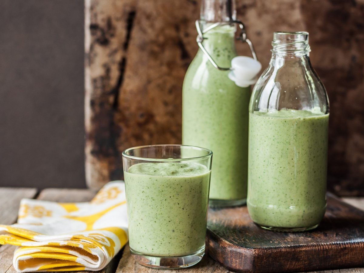 Frontal: Zwei Flaschen und ein Glas mit kalte Gurkensuppe und Wasabi in eine rustikalen Umfeld.