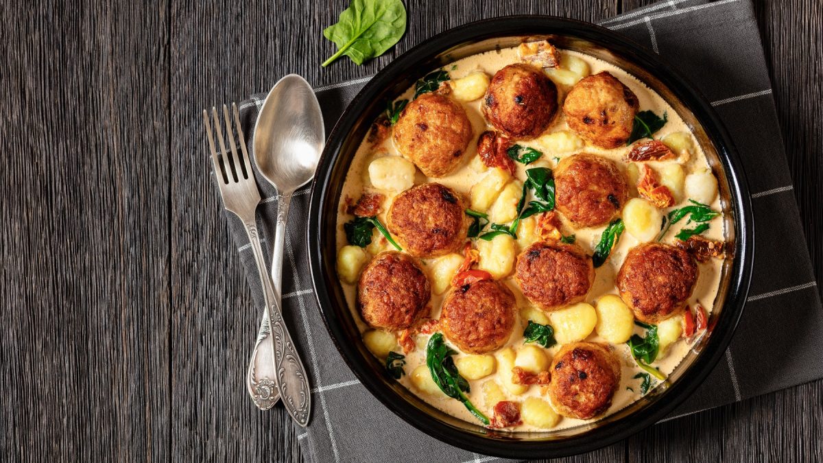 Hähnchenfrikadellen in einer Sahnesauce mit Gnocchi von oben fotografiert.