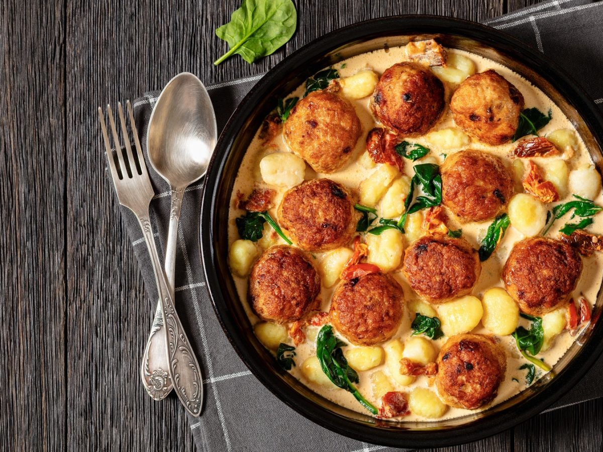 Hähnchenfrikadellen in einer Sahnesauce mit Gnocchi von oben fotografiert.