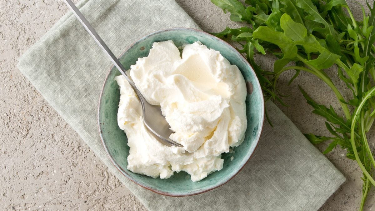 Selbstgemachte Mascarpone in einer blauen Schüssel von oben fotografiert.