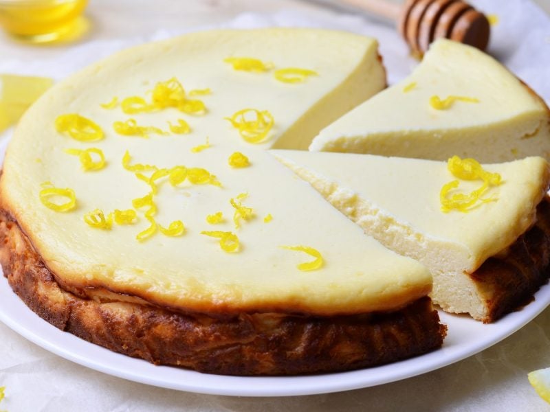 Angeschnittene Melopita mit frischer Zitronenschale von schräg vorne fotografiert.