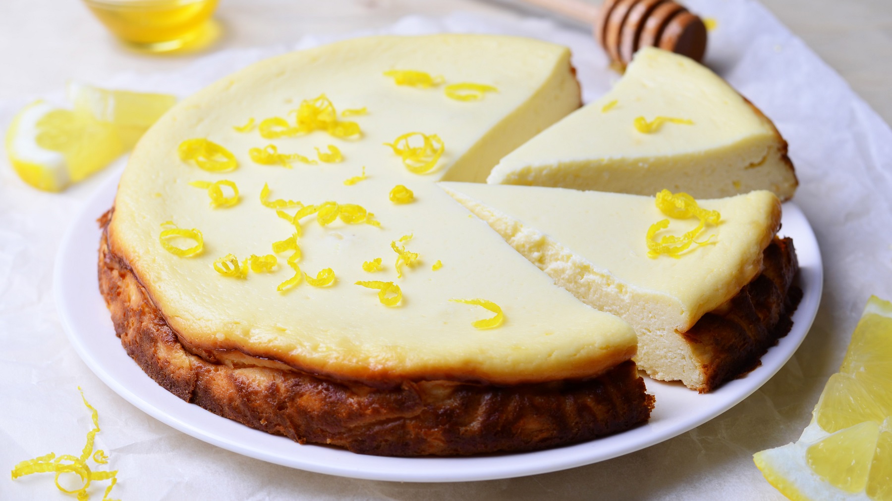 Angeschnittene Melopita mit frischer Zitronenschale von schräg vorne fotografiert.