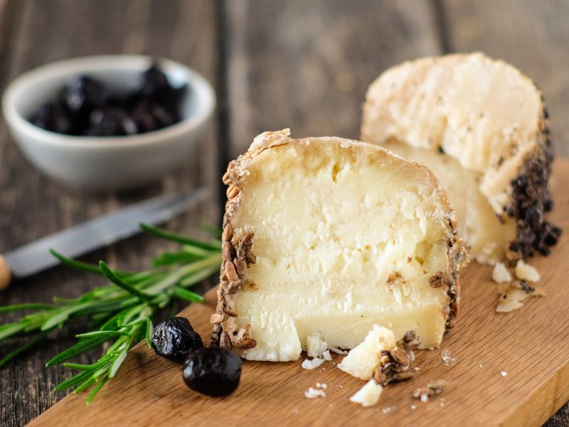 Stücke von pecorino romano von vorne fotografiert auf einem Holzbrett.