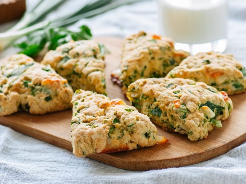 Scones mit Spinat und Feta von schräg oben fotografiert auf einem Holzbrett.