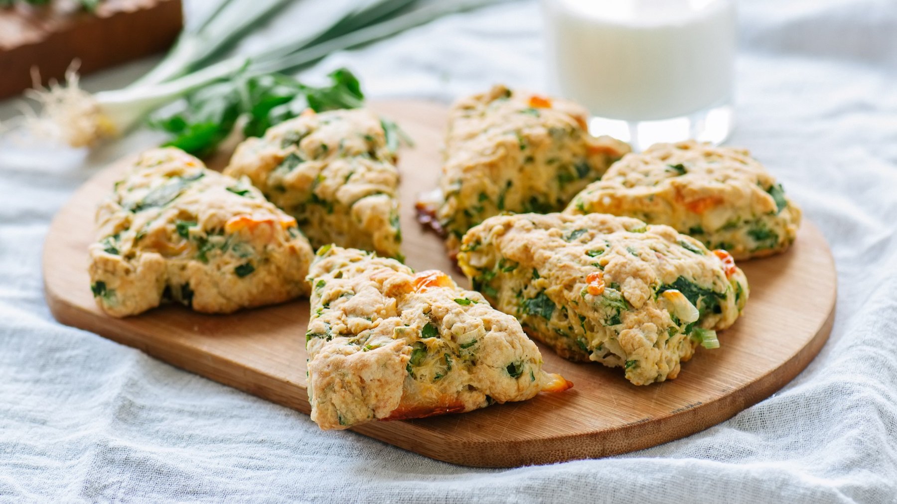 Scones mit Spinat und Feta von schräg oben fotografiert auf einem Holzbrett.