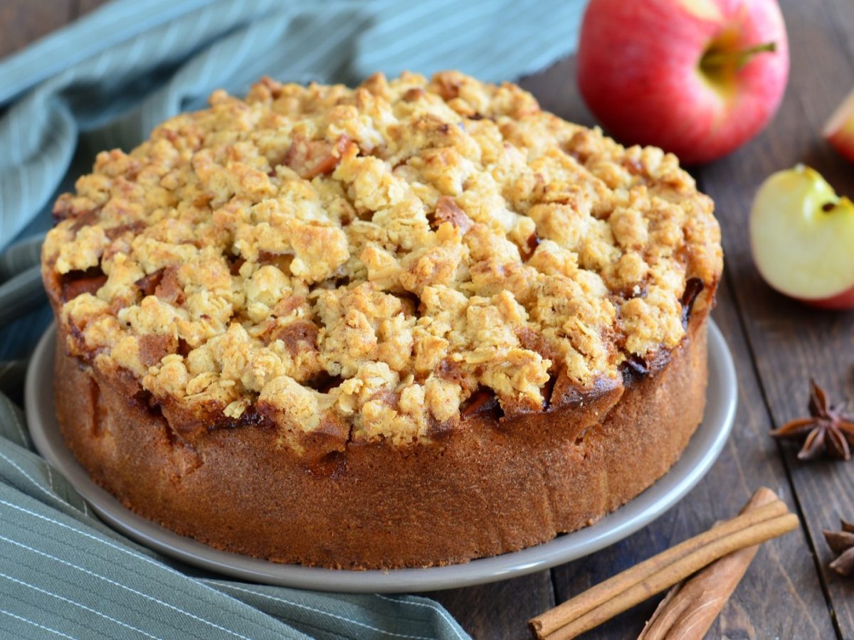 Apfeltorte von vorne fotografiert, daneben Zimtstange, Anissterne und Äpfel.