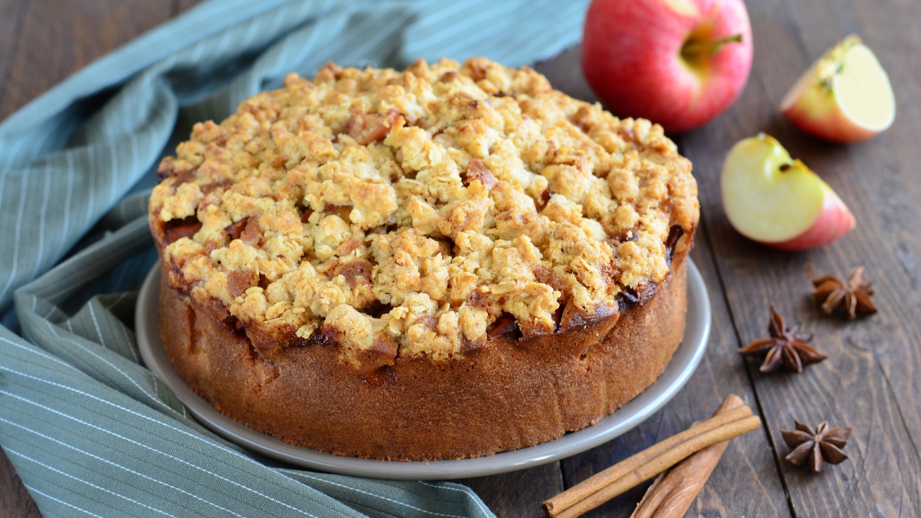 Apfeltorte von vorne fotografiert, daneben Zimtstange, Anissterne und Äpfel.