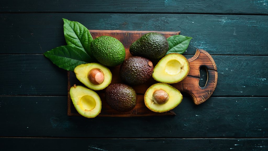 Low-Carb-Lebensmittel: Angeschnittene Avocado von oben fotografiert vor einem dunklen Hintergrund.