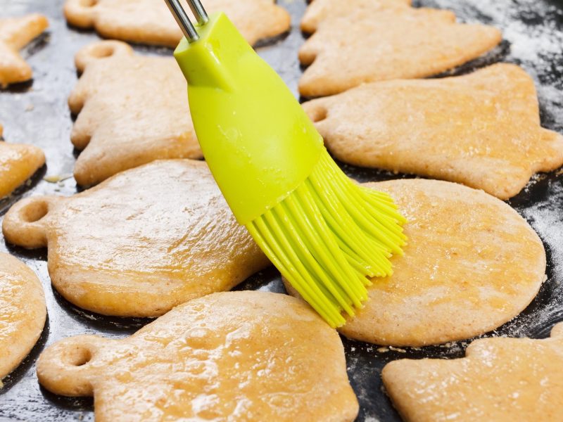 Ein grüner Pinsel streicht Plätzchen mit ein / Plätzchen mit Eigelb