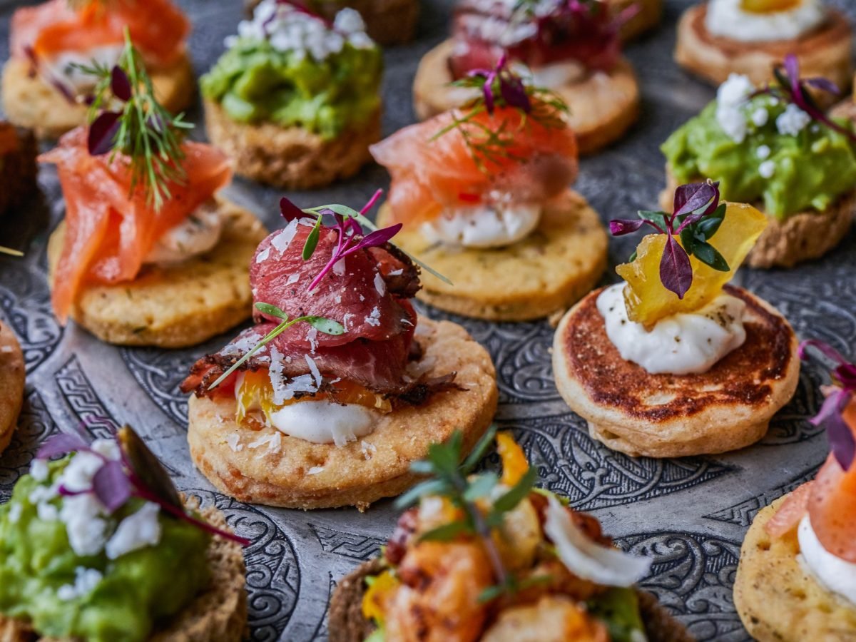 Verschiedenes Fingerfood auf einem dunklen Tisch. Alles von schräg oben und relativ nah fotografiert.