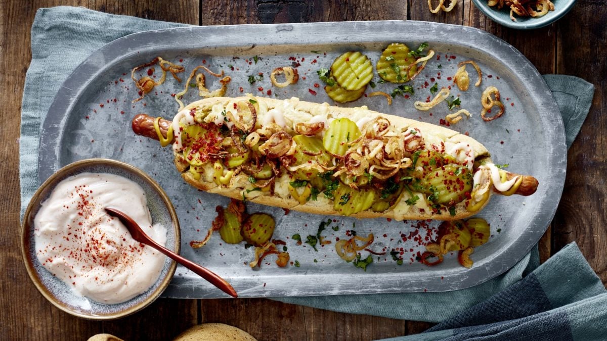 Hotdog ofengebacken im Kräuterbaguette in der Draufsicht.