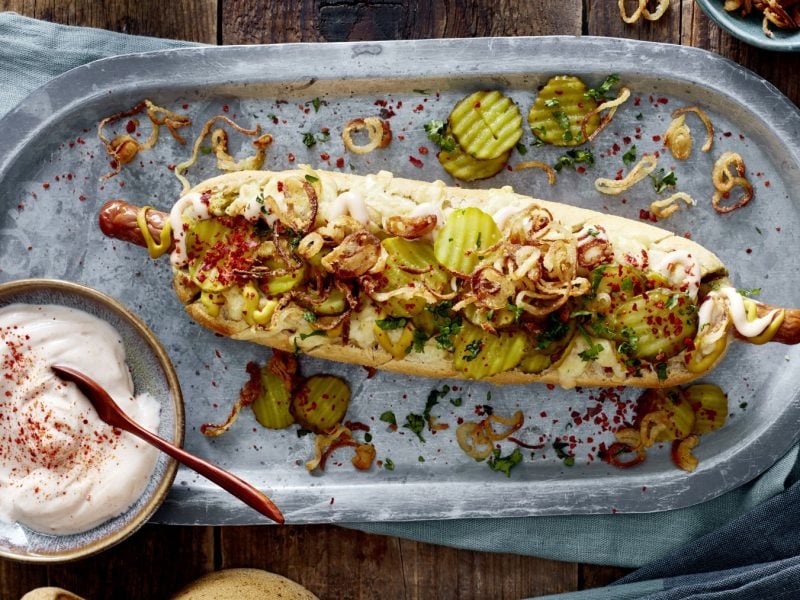 Hotdog ofengebacken im Kräuterbaguette in der Draufsicht.