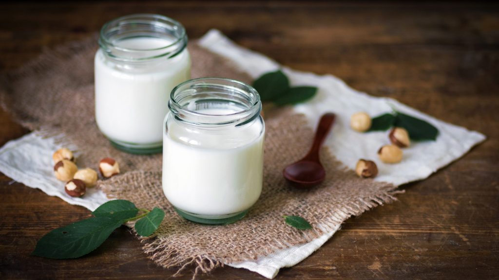 Zwei Gläser mit kohlenhydratarmem Joghurt auf einem dunklen Untergrund.