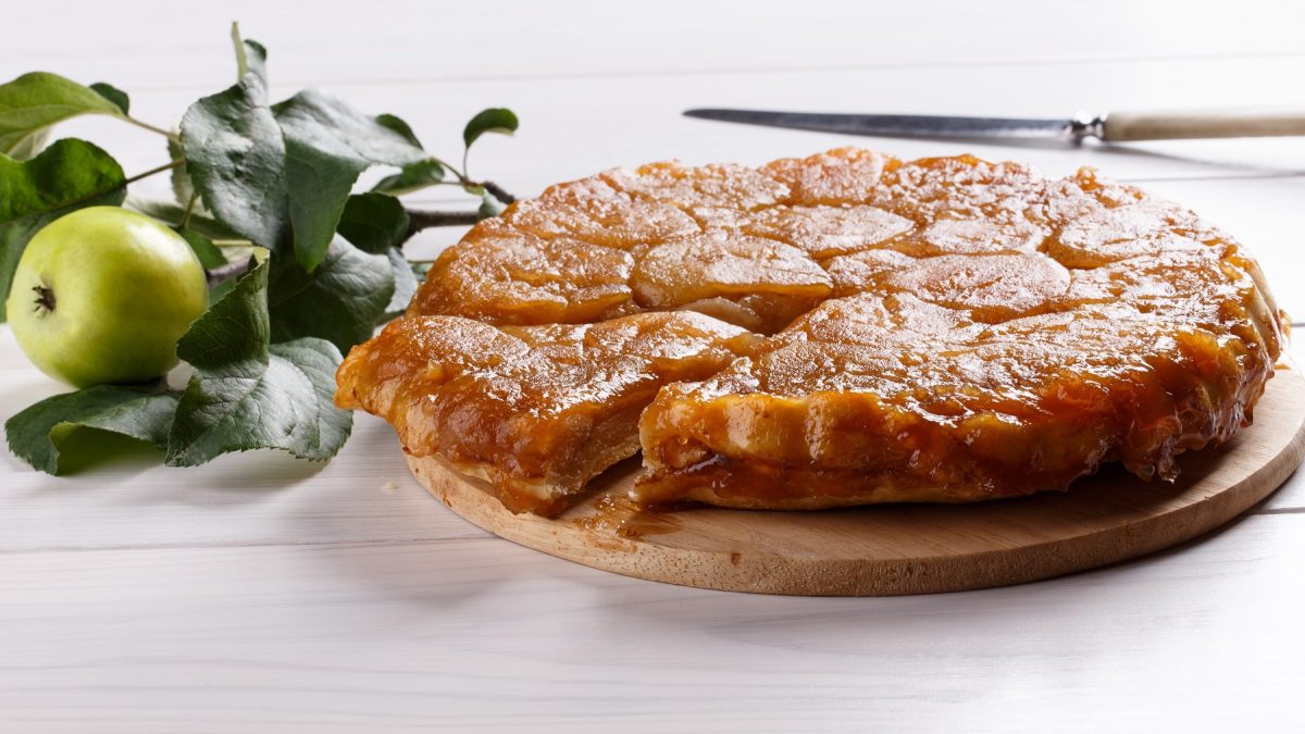 Die Tarte-Tatin auf einem weißen Holztisch von der Seite fotografiert.