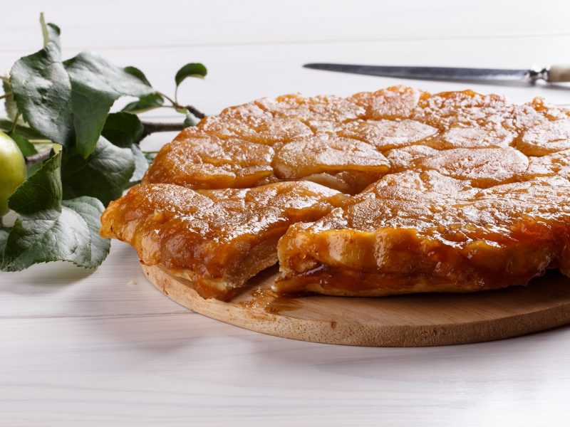 Die Tarte-Tatin auf einem weißen Holztisch von der Seite fotografiert.