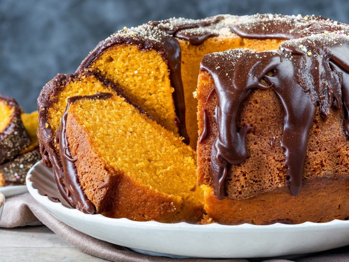 Angeschnittener Bolo de cenoura mit Brigadeiro auf einem weißen Teller von vorne fotografiert.