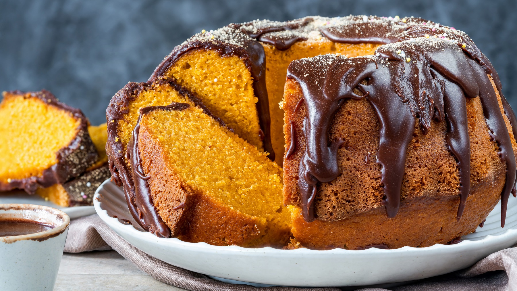 Angeschnittener Bolo de cenoura mit Brigadeiro auf einem weißen Teller von vorne fotografiert.