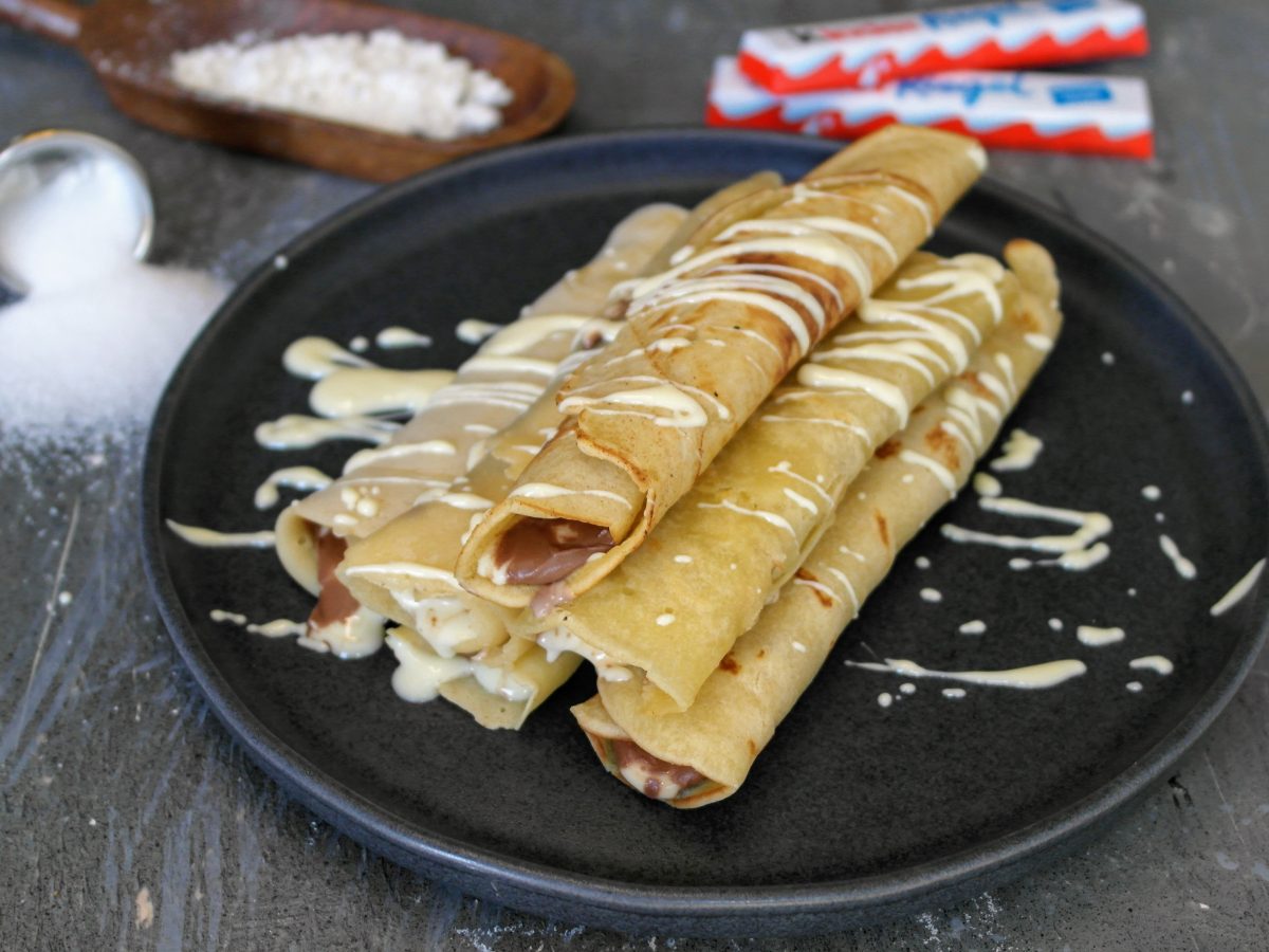 Ein schwarzer Teller mit den Pfannkuchen mit Kinderriegeln.