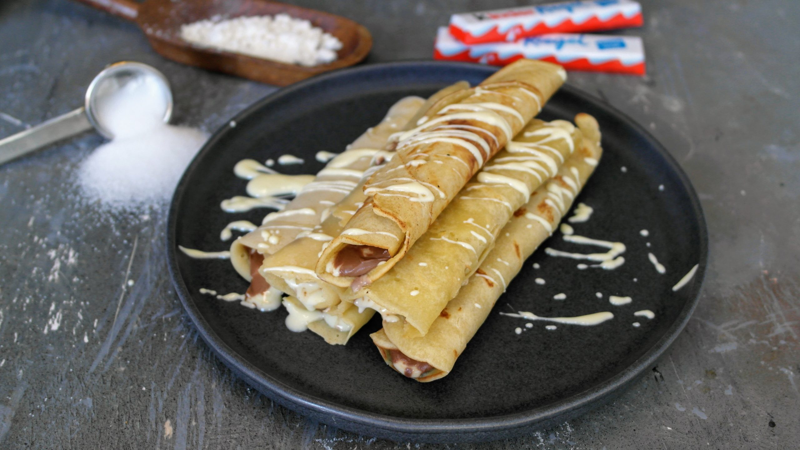 Ein schwarzer Teller mit den Pfannkuchen mit Kinderriegeln.