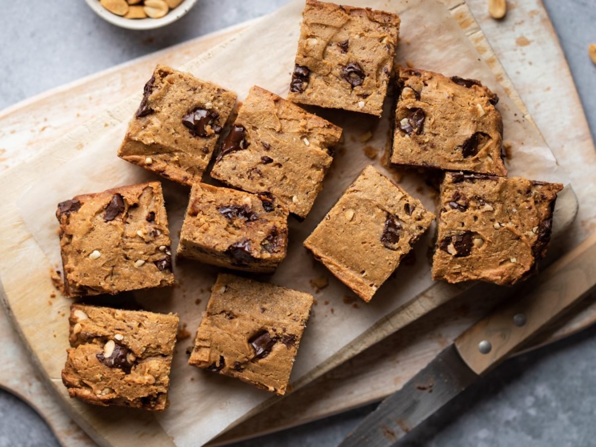 Cookie-Dough-Bars auf einem Holzbrett auf grauem Hintergrund.