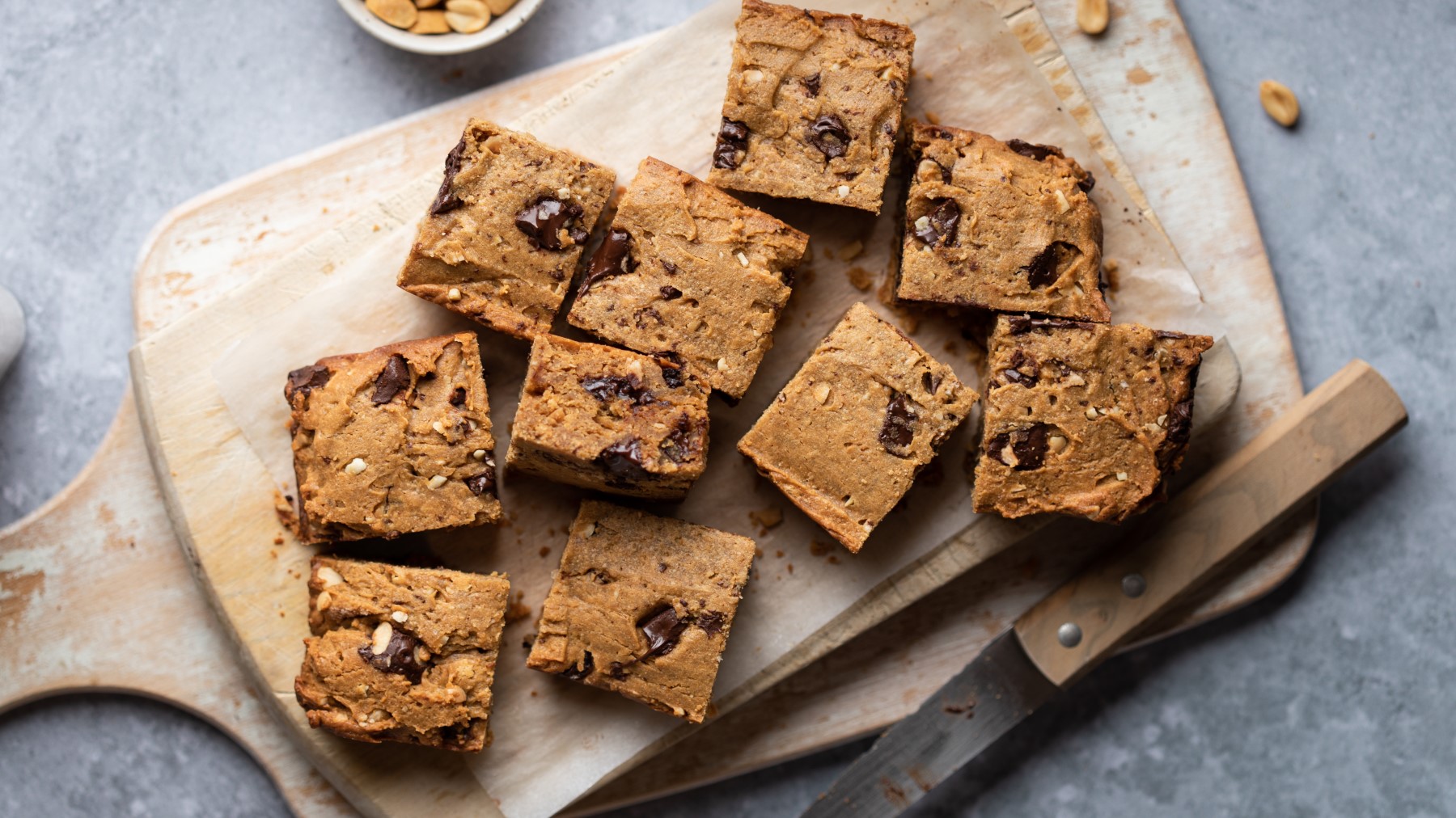 Cookie-Dough-Bars auf einem Holzbrett auf grauem Hintergrund.