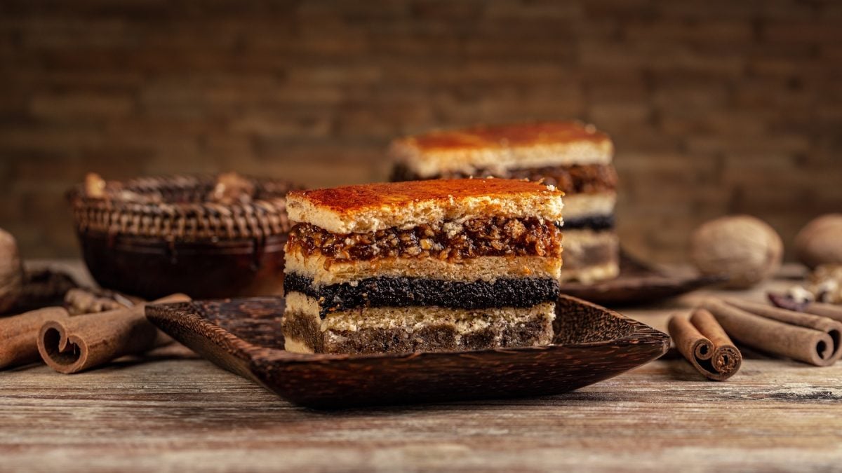 Zwei Stücke Flódni bzw., Fächertorte von vorne fotografiert. Daneben Zimtstangen und Walnüsse.