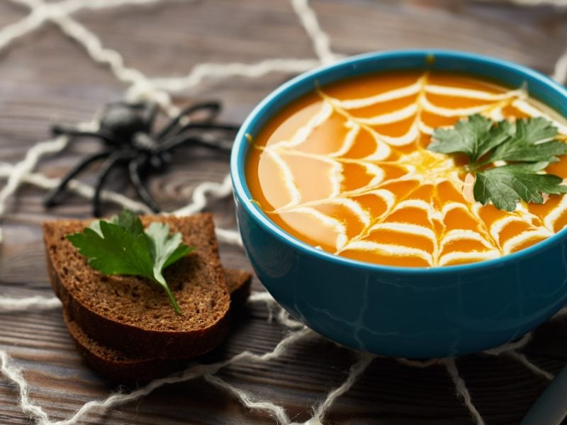 Halloween-Kürbissuppe auf hölzernem Hintergrund.