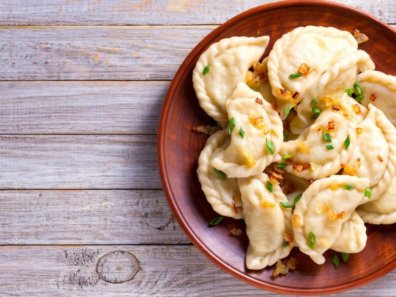 Kürbis-Curry-Dumplings auf einem braunen Teller auf grauem Hintergrund.