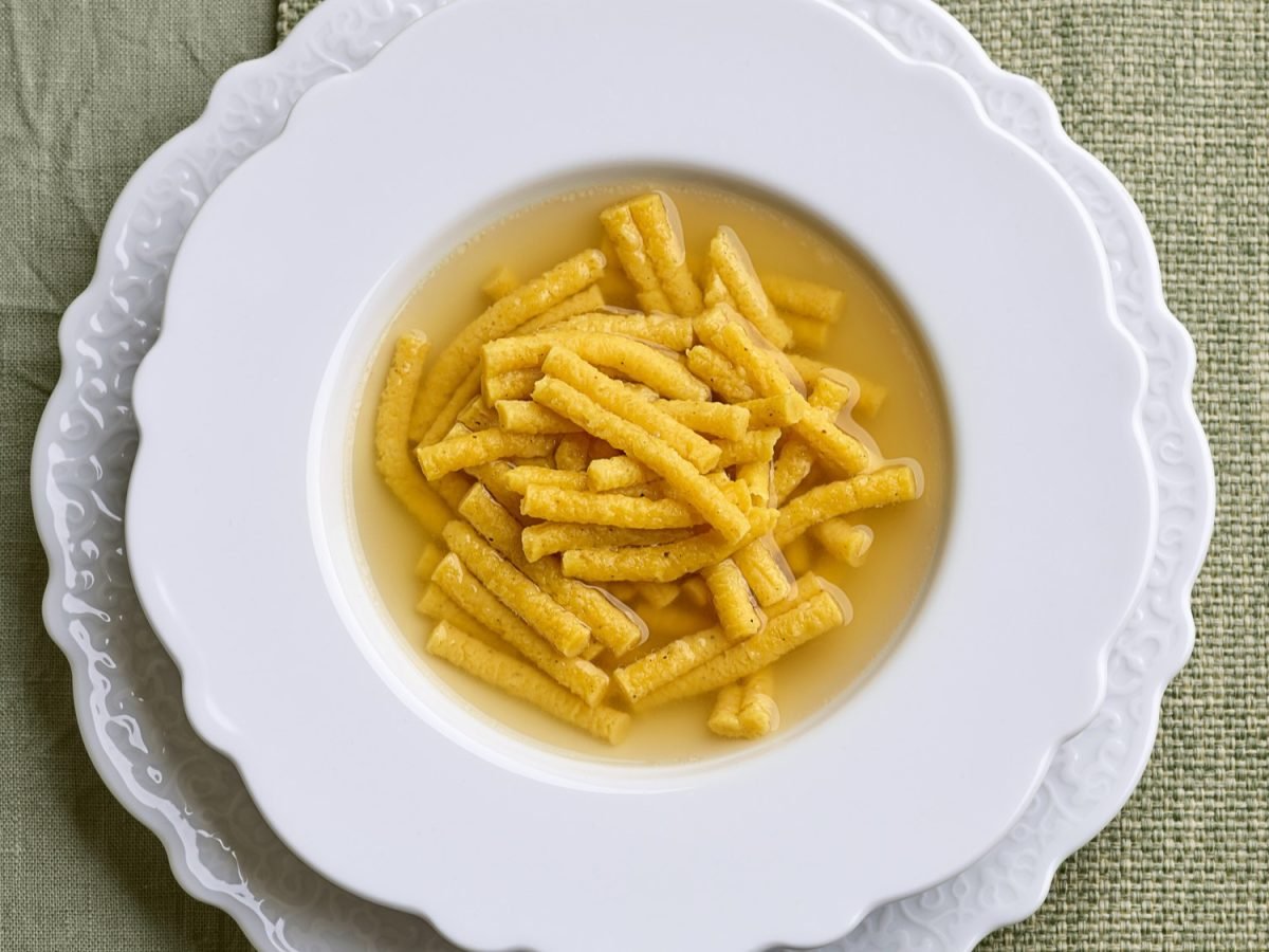 Passatelli in Brühe in einem weißen Suppenteller von oben fotografiert.