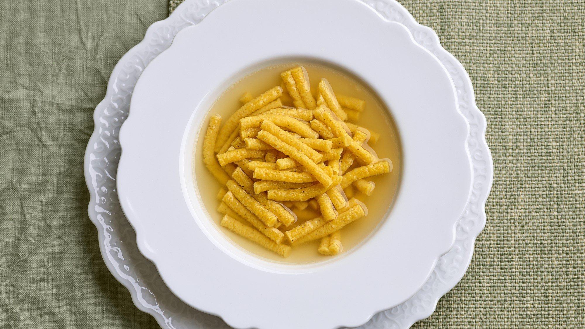 Passatelli in Brühe in einem weißen Suppenteller von oben fotografiert.