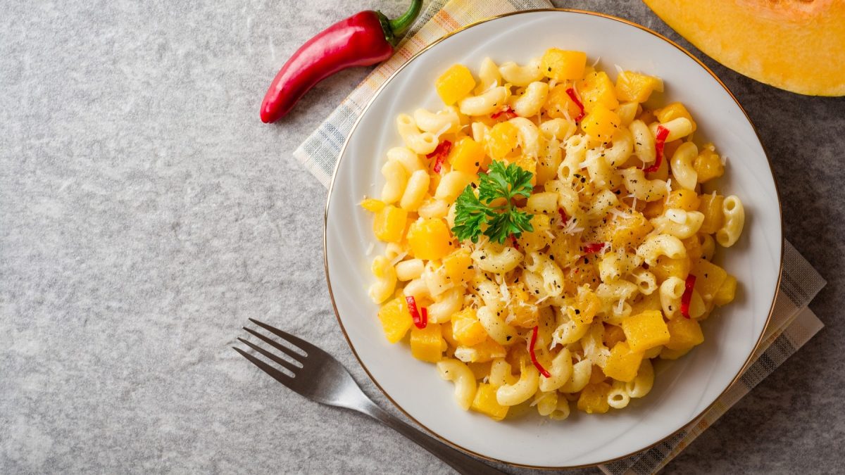 Pasta e coccozza auf einem weißen Teller, daneben Chilischote. Von oben fotografiert.