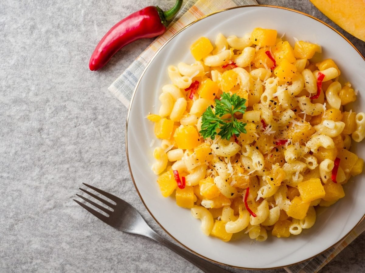 Pasta e coccozza auf einem weißen Teller, daneben Chilischote. Von oben fotografiert.