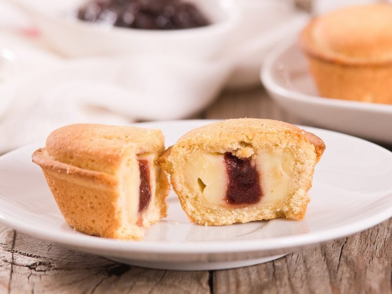 Angeschnittener Pasticciotto napoletano auf einem weißen Teller von vorne fotografiert.