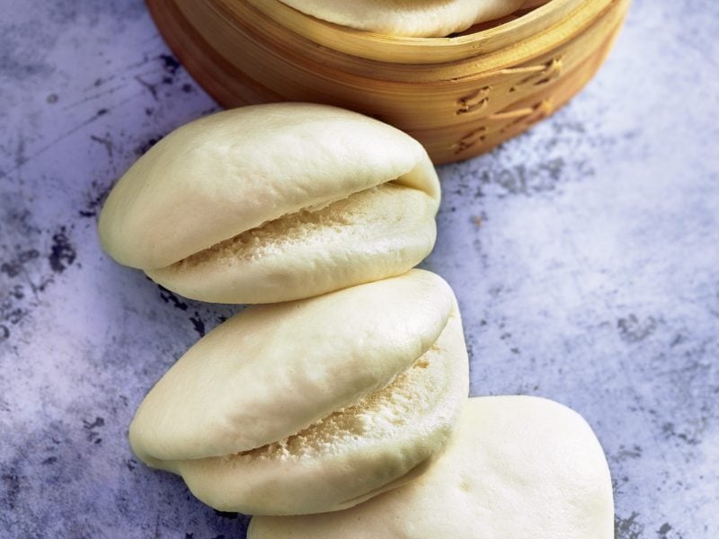 Die Bao-Buns mit einem Dämpfkorb auf einem Marmortisch von oben fotografiert.