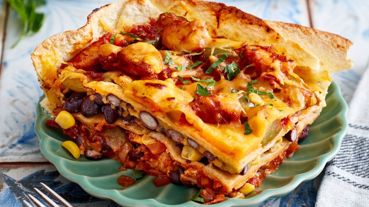 Tortilla-Hähnchen-Lasagne auf einem grünen Teller auf hellem Hintergrund.